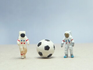 Mini toy of action figure at outdoor with blurred background. Toy photography concept design. Astronaut at space with ball. Sportsman playing football at moon.