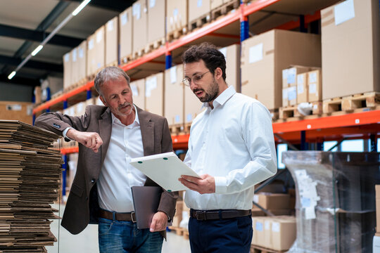 Senior businessman with colleague discussing over document at warehouse