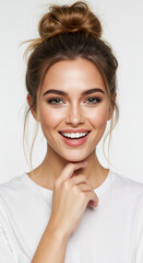Naklejka premium Woman with high messy bun hairstyle and face framing tendrils touching chin on white background. Casual updo styling demonstration for salon hair arrangement services