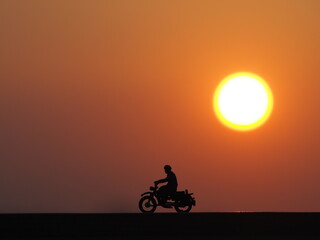 View of sunrise time with orange sky. Background is blurred. Mini toy of action figure at outdoor with blurred background. Toy photography concept design.