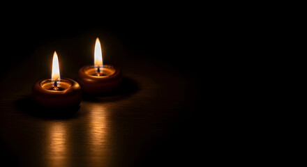 Two burning candles on dark background