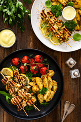 Greek style chicken skewers souvlaki with roasted potatoes and cherry tomatoes on wooden background	