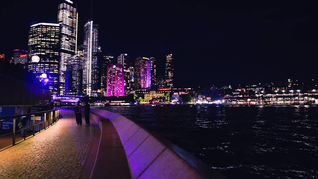 Sydney, Australia - June 11, 2025: HD Video - Colourful Sydney City Skyline by night at East Circular Quay during Vivid Sydney Lights Festival. Free annual outdoor event of light music and ideas.