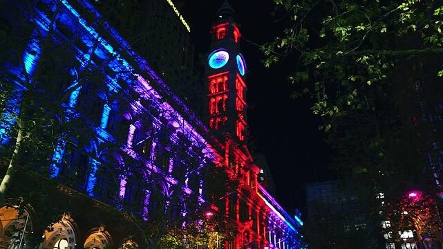 Sydney, Australia - June 11, 2025: HD Video -Looking up at colourful light projections on the Martin Place clock tower post office building during Vivid Sydney Lights Festival. 