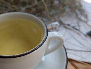 white ceramic cup and saucer with green herbal tea placed on a table