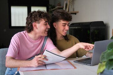 Two students smiling and using laptop for studying at home