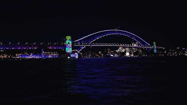 Sydney, Australia - June 11, 2025: HD Video - Colourful Sydney City Waterfront by night at Harbour Bridge during Vivid Sydney Lights Festival. Free annual outdoor event of light, music and ideas.
