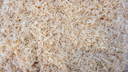 Detailed close-up view of natural wood shavings or sawdust showcasing intricate textures often used as bedding material, packing, pet litter or craft resources.