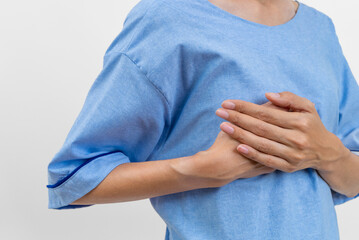 Close up asian woman cancer wearing patient gown with hands examining breast lump for signs of...
