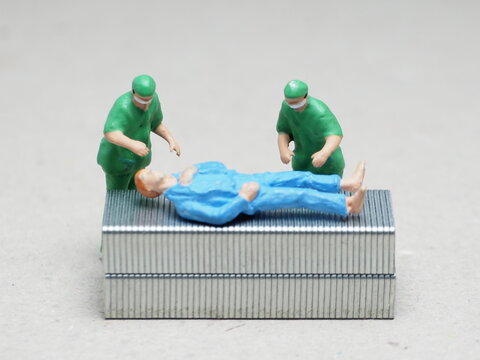 Mini toy of action figure at table with blurred background. Macro toy photography concept design. Minifigure of doctor and patient character at surgery room.