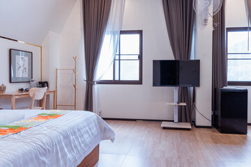 Modern bedroom with wooden floor and t cell cancer awareness decoration on bedspread near window with curtains and television on stand in bright natural light