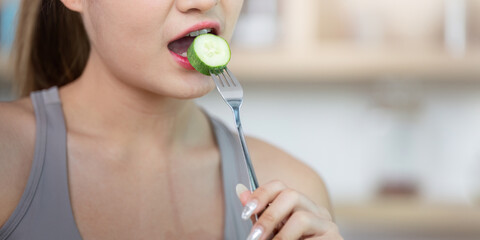 Wellness and Healthy Eating. Woman enjoying cucumber slice for nutritious diet.