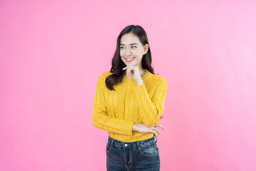 The Asian female model, posing confidently while taking photos in a studio with a pink background,...