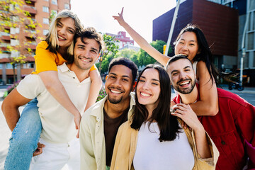 Diverse group of young happy friends smile at camera outside. Friendship and youth community concept.