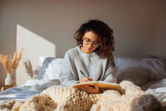Young woman writing in self-reflection journal under warm light. A peaceful scene of a woman journaling under soft light, capturing a moment of self-awareness, emotional healing, and mindful expressio