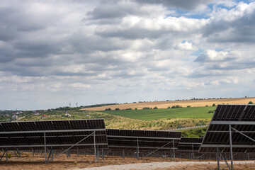 Large solar panel installation in rural landscape under dramatic cloudy sky. Clean energy...