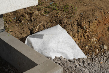 A detailed photo of the exterior of the building. We can see the edge of the curb and the non-woven fabric that is buried underground.
