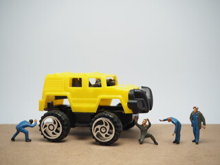 Mini toy of action figure at table with blurred background. Automotive photography concept design. Minifigure of mechanic crew character with big monster truck at garage. © awstoys