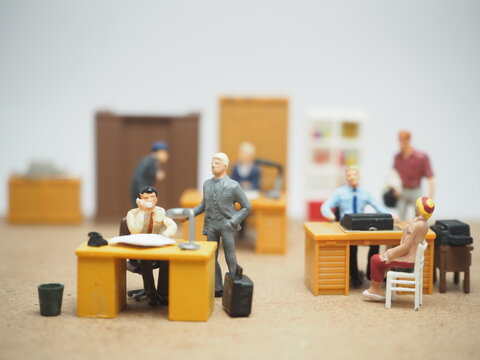 Mini toy of action figure at table with blurred background. Diorama photography concept design. Minifigure office workers casually interacting on office, symbolic of quiet quitting culture.