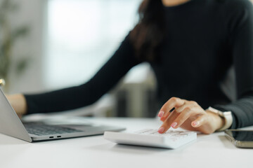 Businesswoman calculating expenses and working on laptop in office