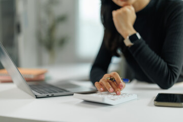 Businesswoman calculating expenses using calculator in office