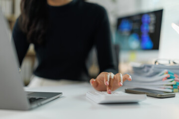 Businesswoman calculating expenses using calculator in office