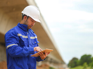 Asian engineer working with tablet at site of a large building project,Thailand people,Work overtime at construction site