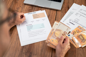 Old man tenant prepares euro banknotes to pay for utility bill at wooden table closeup, mature male...