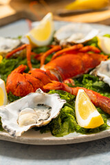 Delicious lobster and oysters lying on seaweed with lemon wedges