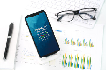 A smartphone displaying an Commodity Market Outlook report is placed atop a stack of papers with...