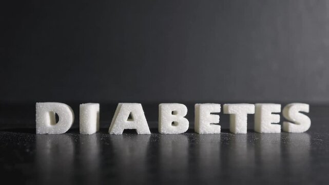 White sugar cubes form the word diabetes on a reflective black surface, highlighting the link between sugar consumption and this metabolic disease