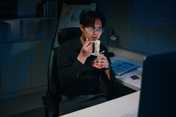 Male employee having a quick meal while working overtime on important projects in the office