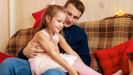 Father and daughter playing together in front of the Christmas tree