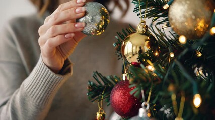 Person decorates a Christmas tree with festive ornaments, capturing the holiday spirit and creating a warm, inviting atmosphere. - Powered by Adobe