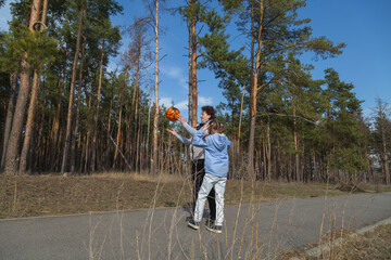 Little girl with grandmother playing a ball in forest