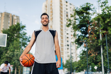 Basketball player smiling on court holding ball