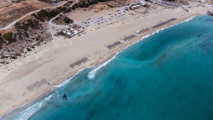 Aerial drone views of Falasarna Beach highlight its wide stretch of golden sand and vivid turquoise...