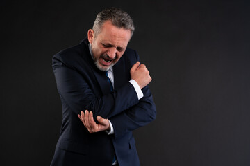 Businessman in pain holding his elbow