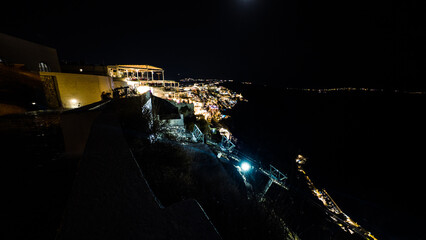 Imerovigli shines beautifully at night, with its white buildings illuminated against the dark sky. Captured in long exposure