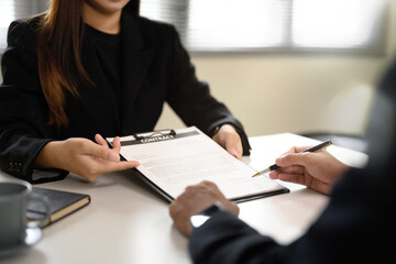 Close up of hands reviewing and signing a formal agreement at office desk