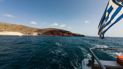 Red Beach in Santorini is famous for its striking red volcanic cliffs and crystal-clear blue waters. Bright daylight highlights the vivid colors, creating a dramatic and beautiful natural landscape