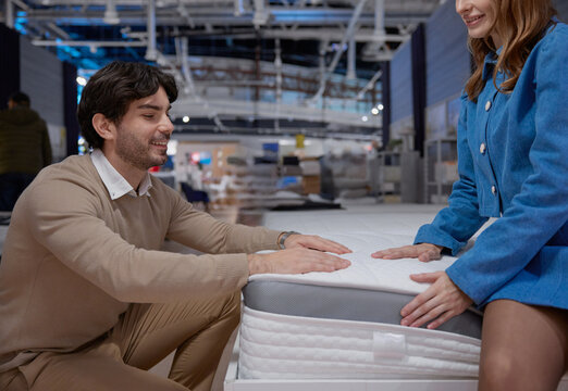 A couple engaging in the process of shopping for a new mattress at a furniture showroom