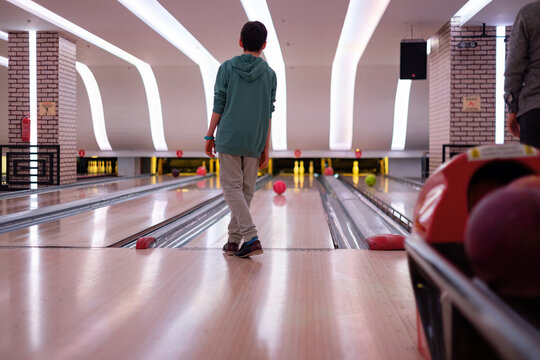 Son in a bowling alley striking pins with precision