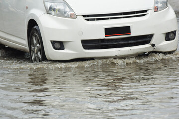 Car passing through a flooded road, flood caused by torrential rains. Flooded city road with a...