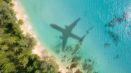 Aerial view of shadow passenger plane silhouette and sandy beach blue sea with waves at sea beach...