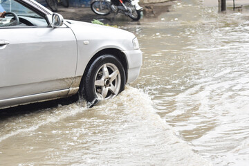 Car passing through a flooded road, flood caused by torrential rains. Flooded city road with a...
