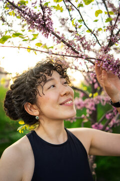 Woman appreciating cherry blossoms in garden