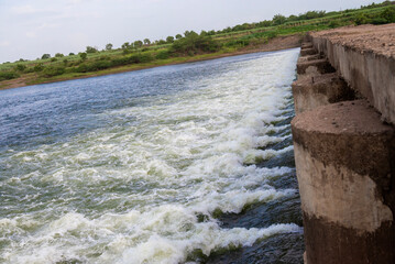 Rapidly flowing water with large waves over a dam on a river, water flow at the dam gate