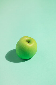 Green apple on vibrant surface with soft shadow