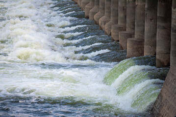 Rapidly flowing water with large waves over a dam on a river, water flow at the dam gate